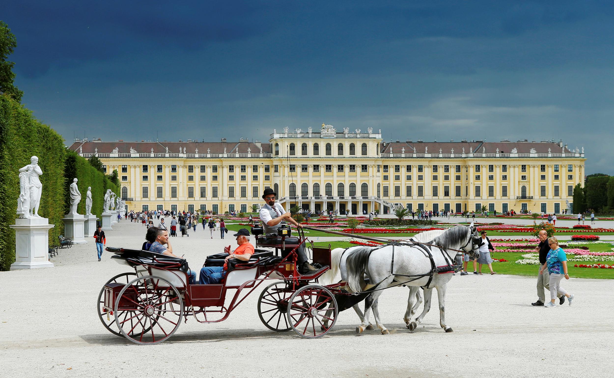 A traditional Fiaker horse carriage passes the imperial Schoenbrunn palace in Vienna, Austria