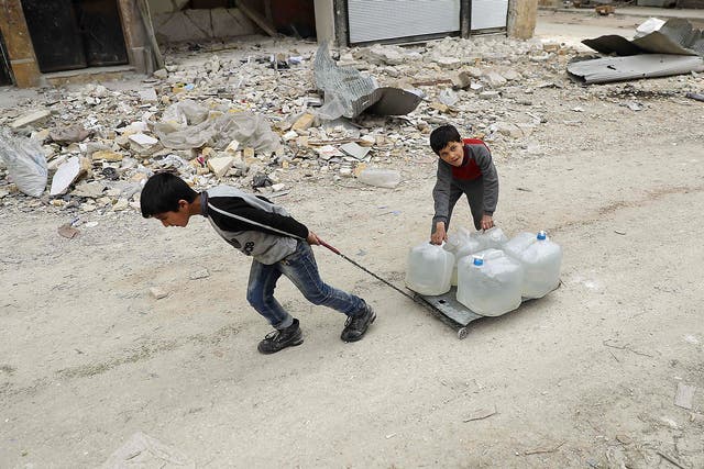 A Syrian child pulls a plastic crate carrying water bottle in the once rebel-held Shaar neighbourhood in Aleppo