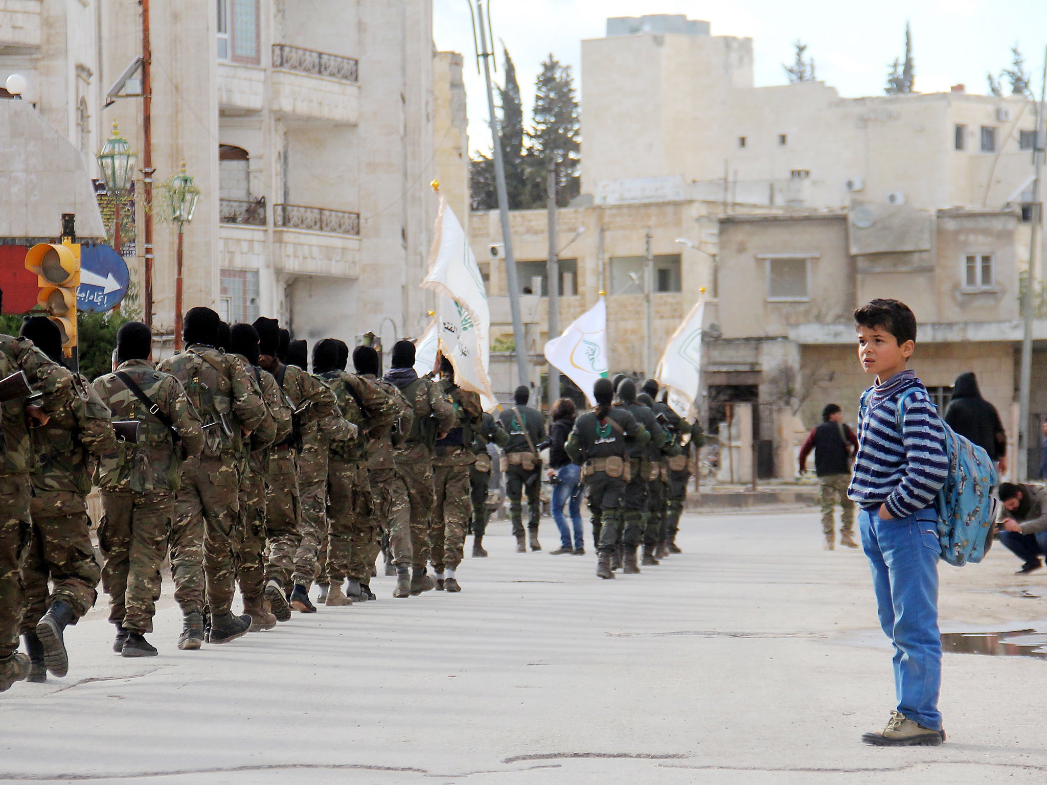 &#13;
A Syrian boy looks at rebel fighters from the Jaish al-Fatah (or Army of Conquest) brigades, which include other rebel factions, marching in the city of Idlib &#13;