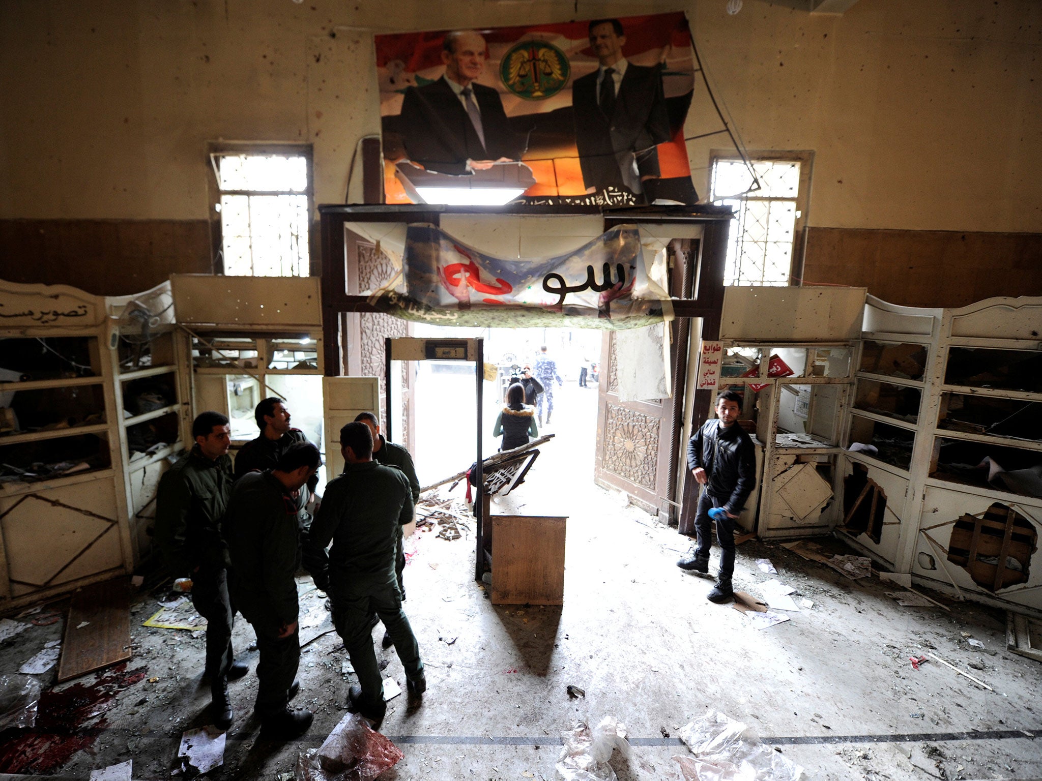 Security personnel stand near a damaged entrance after a suicide blast at the Palace of Justice in Damascus, 15 March