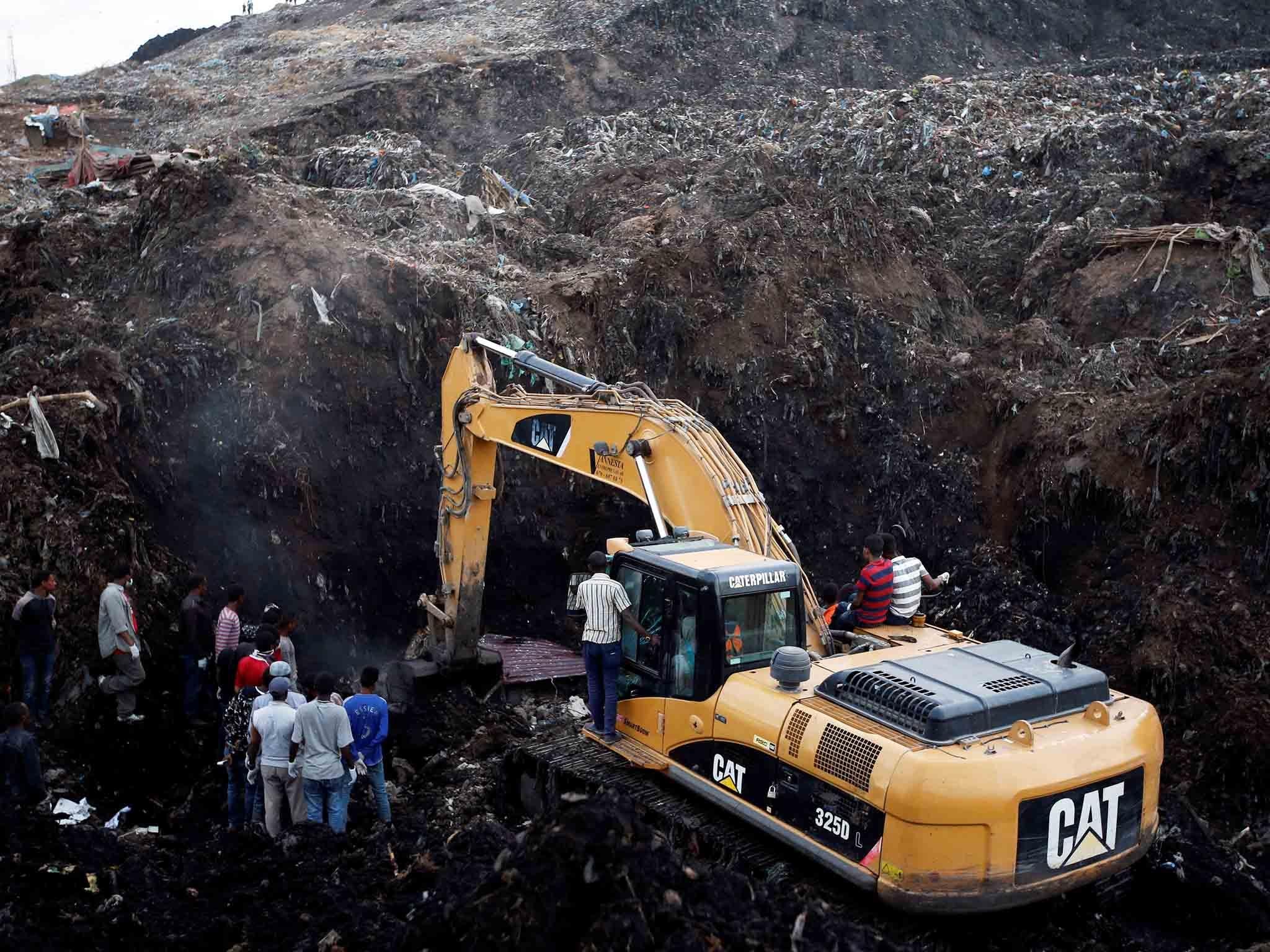Rescue workers watch as excavators dig into a pile of garbage in search of missing people following a landslide when a mound of trash collapsed on an informal settlement at the Koshe garbage dump in Ethiopia's capital Addis Ababa