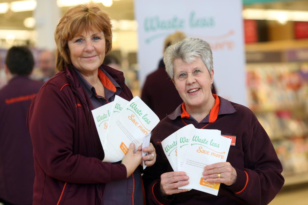 Supermarket employees give out food waste info cards