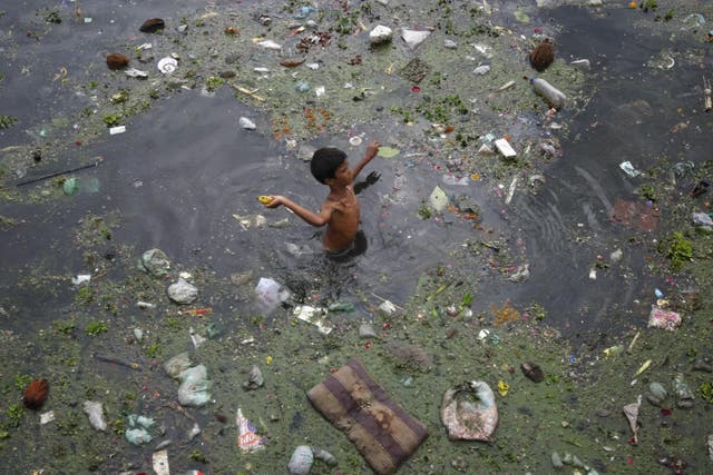 A boy throws a banana after collecting it from the polluted waters of River Sabarmati in Ahmedabad, India
