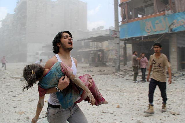 A man carries a young girl injured in a regime barrel bomb attack in the Syrian city of Aleppo on June 3, 2014. Almost 500,000 people have lost their lives in six years of conflict