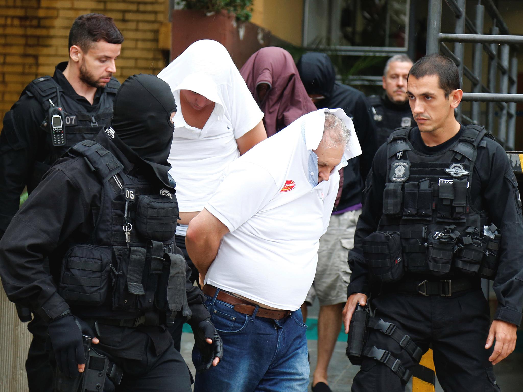 People detained during the probe known as "Operation Weak Flesh" are escorted by the police as they leave the Institute of Forensic Science in Curitiba, Brazil