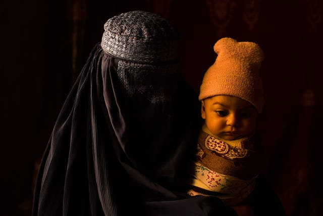 A woman with her child, part of a group of five families in eastern Afghanistan who lived as unregistered refugees for 30 years
