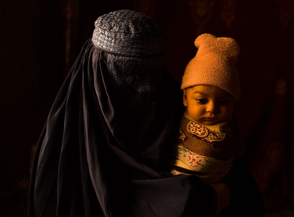 A woman with her child, part of a group of five families in eastern Afghanistan who lived as unregistered refugees for 30 years