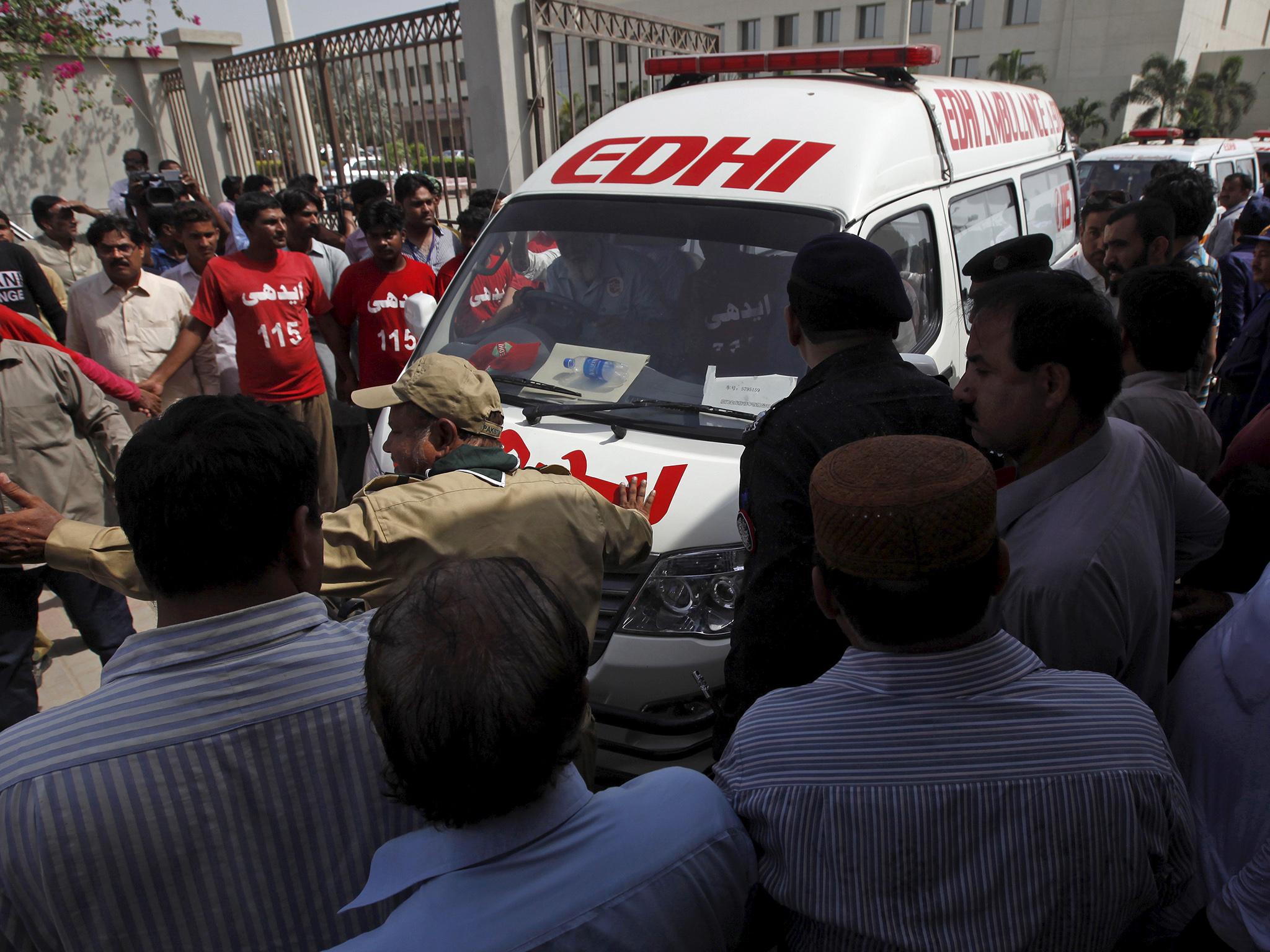 Rescue workers make way for an ambulance carrying victims of an attack on a bus (Akhtar Soomro/Reuters)