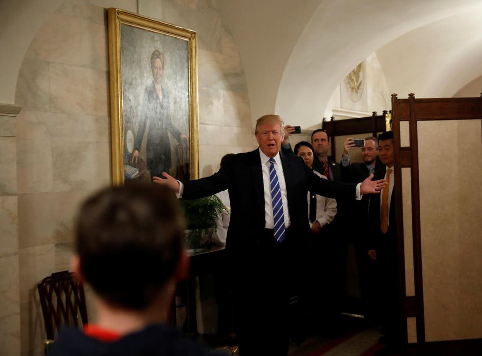 Under a painting of Hillary Clinton, U.S. President Donald Trump makes a surprise appearance in front people touring the White House in Washington, U.S. March 7, 2017