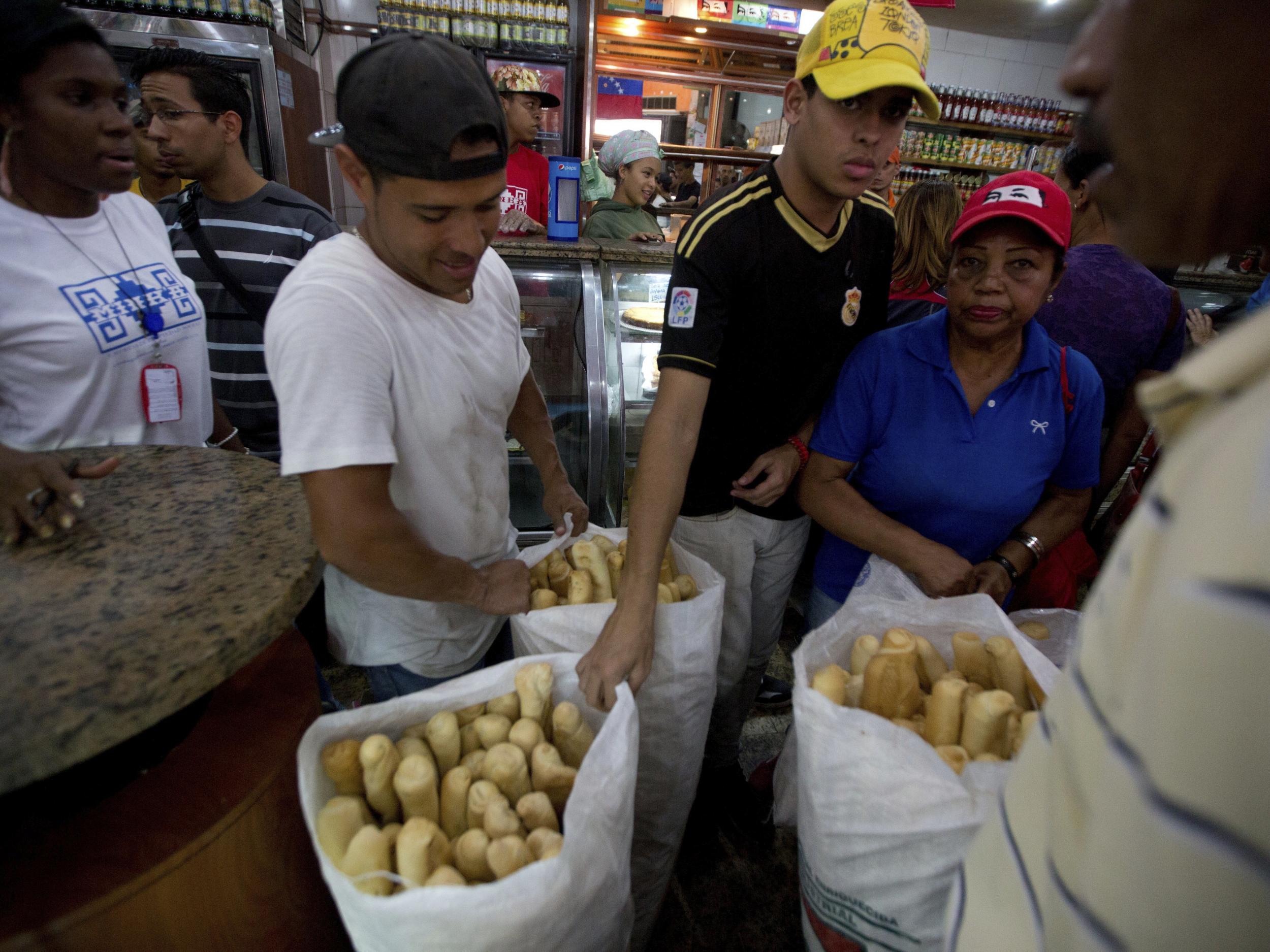 Employees of the Minka state-run bakery carry bags of cheap bread to be distributed to state-run grocery stores in Caracas