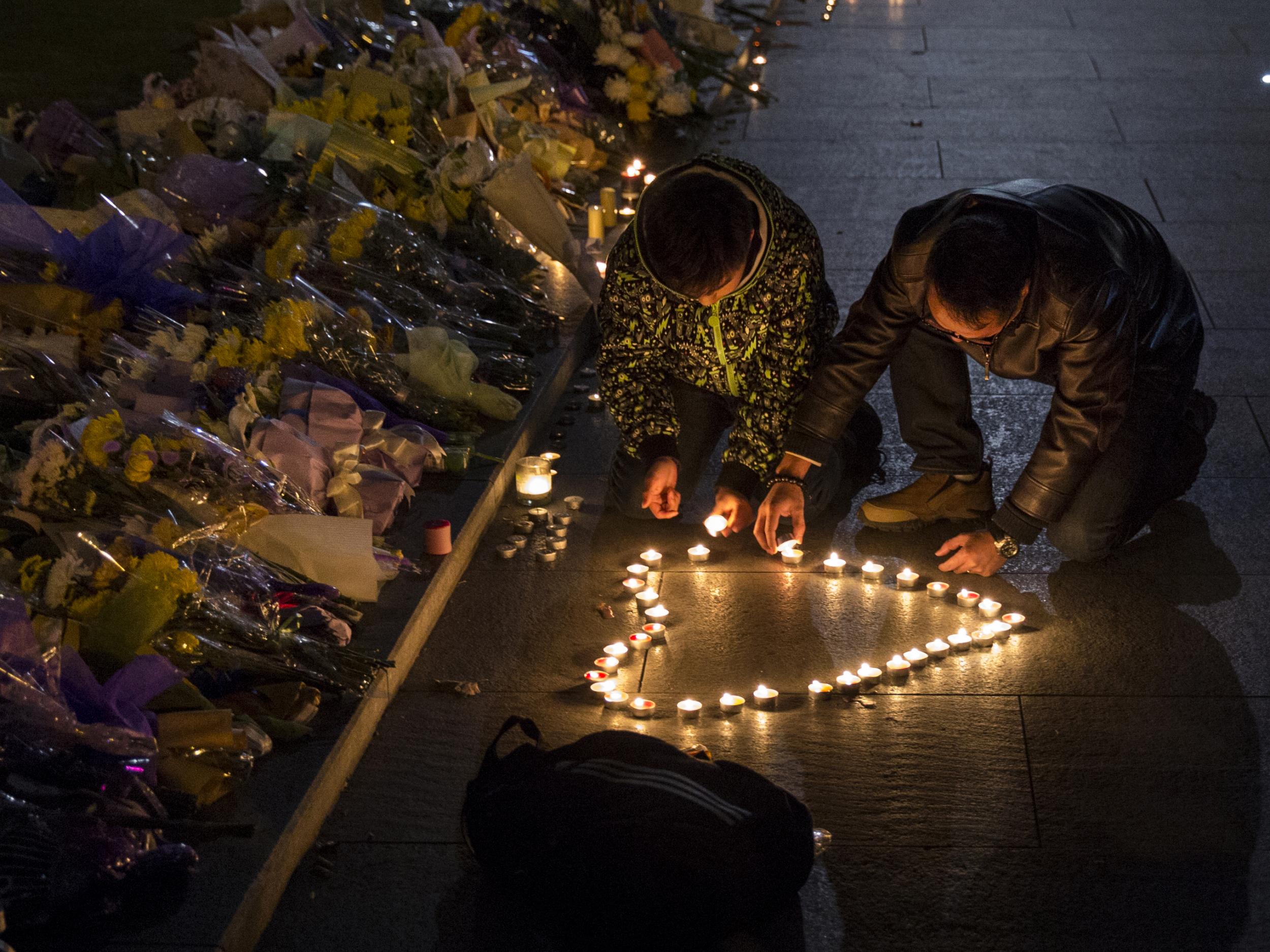 Mourners light candles in the shape of a heart at a makeshift memorial at the site of a stampede on 1 January, 2015