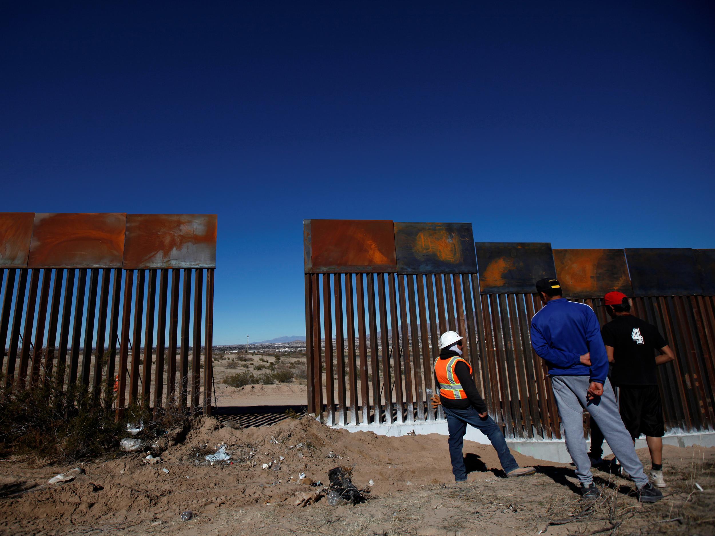 A worker chats with residents at a newly built section of the US-Mexico border fence