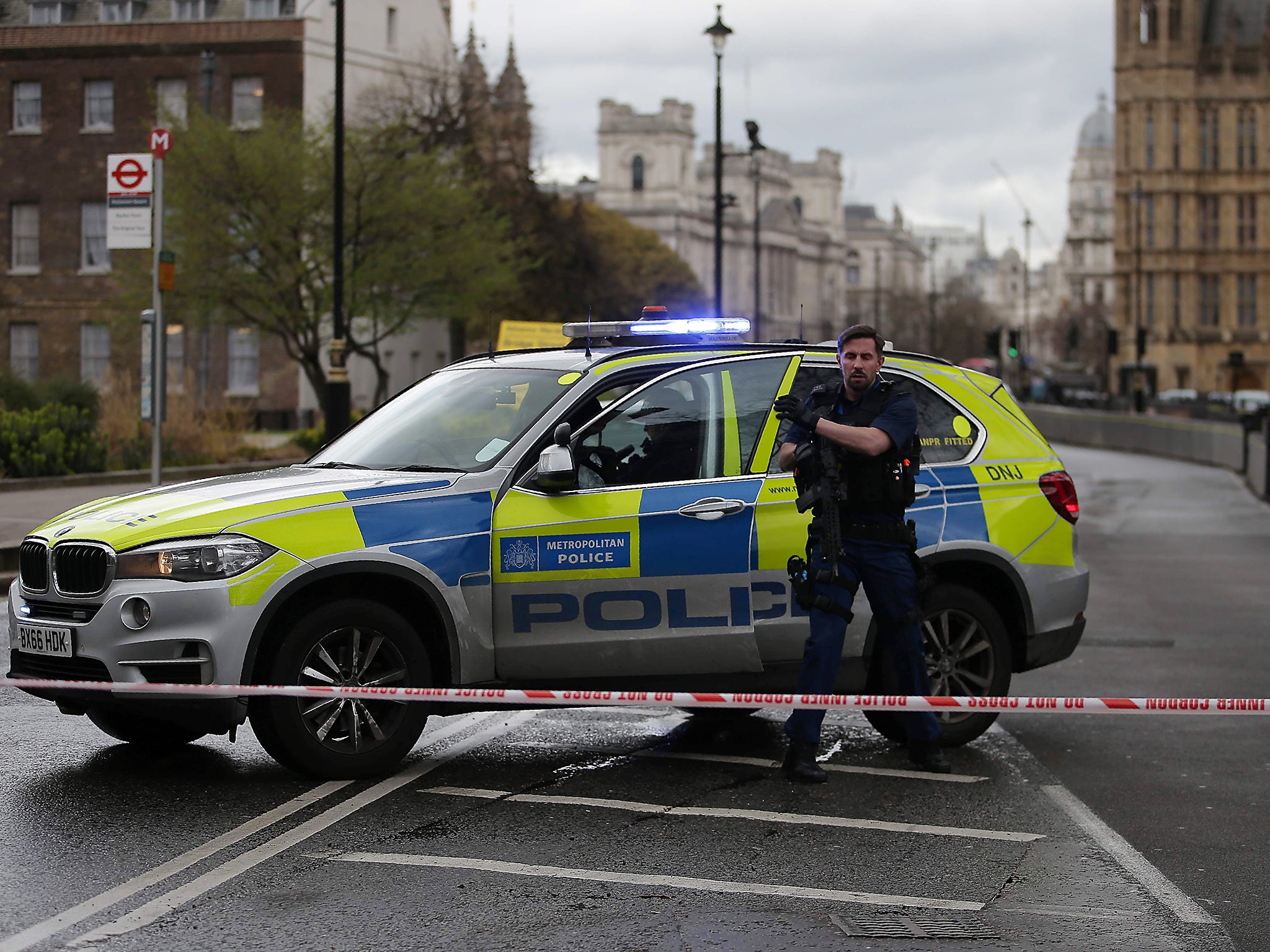 An armed police officer stands guard inside a police cordon outside the Houses of Parliament after the terrorist incident