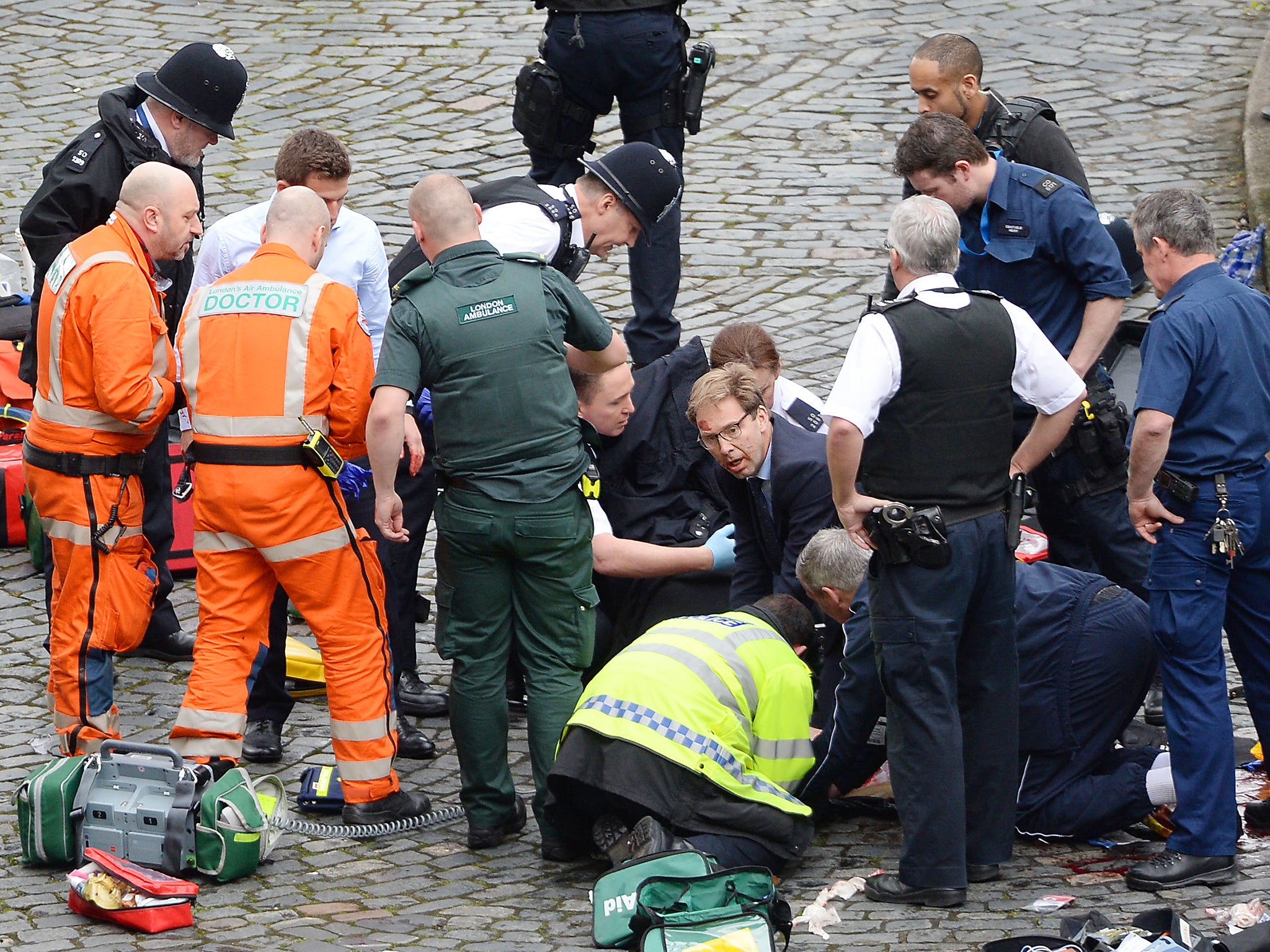 Conservative MP Tobias Ellwood (centre) helps emergency services attend to a police officer outside the Palace of Westminster, London, after a policeman was stabbed and his apparent attacker shot by officers in a major security incident at the Houses of Parliament