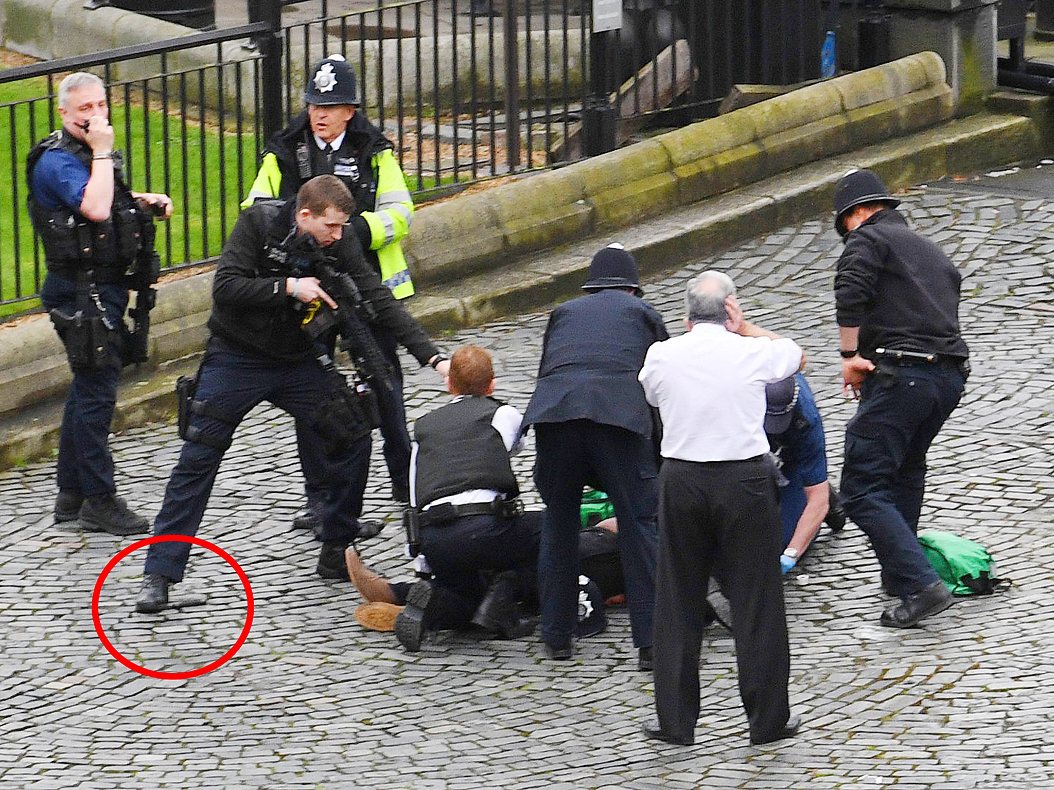 An armed officer stands with his foot on a knife, as medics provide assistance