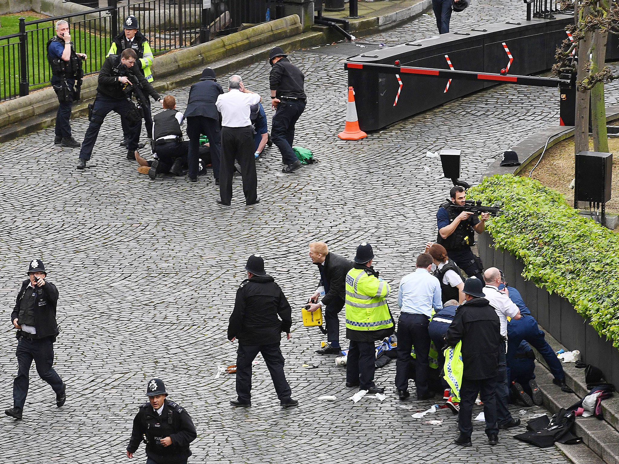 A policeman points a gun at a man on the floor (top) while emergency services attend him and a police officer (bottom) outside the Palace of Westminster, London, after policeman was stabbed and his apparent attacker shot by officers in a major security incident at the Houses of Parliament