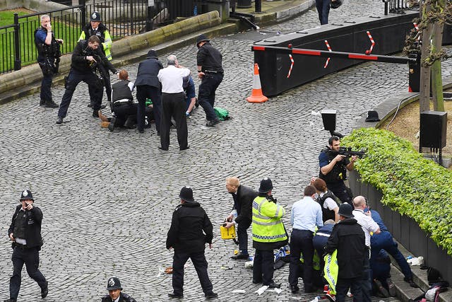 A policeman points a gun at a man on the floor (top) while emergency services attend him and a police officer (bottom) outside the Palace of Westminster, London, after policeman was stabbed and his apparent attacker shot by officers in a major security incident at the Houses of Parliament