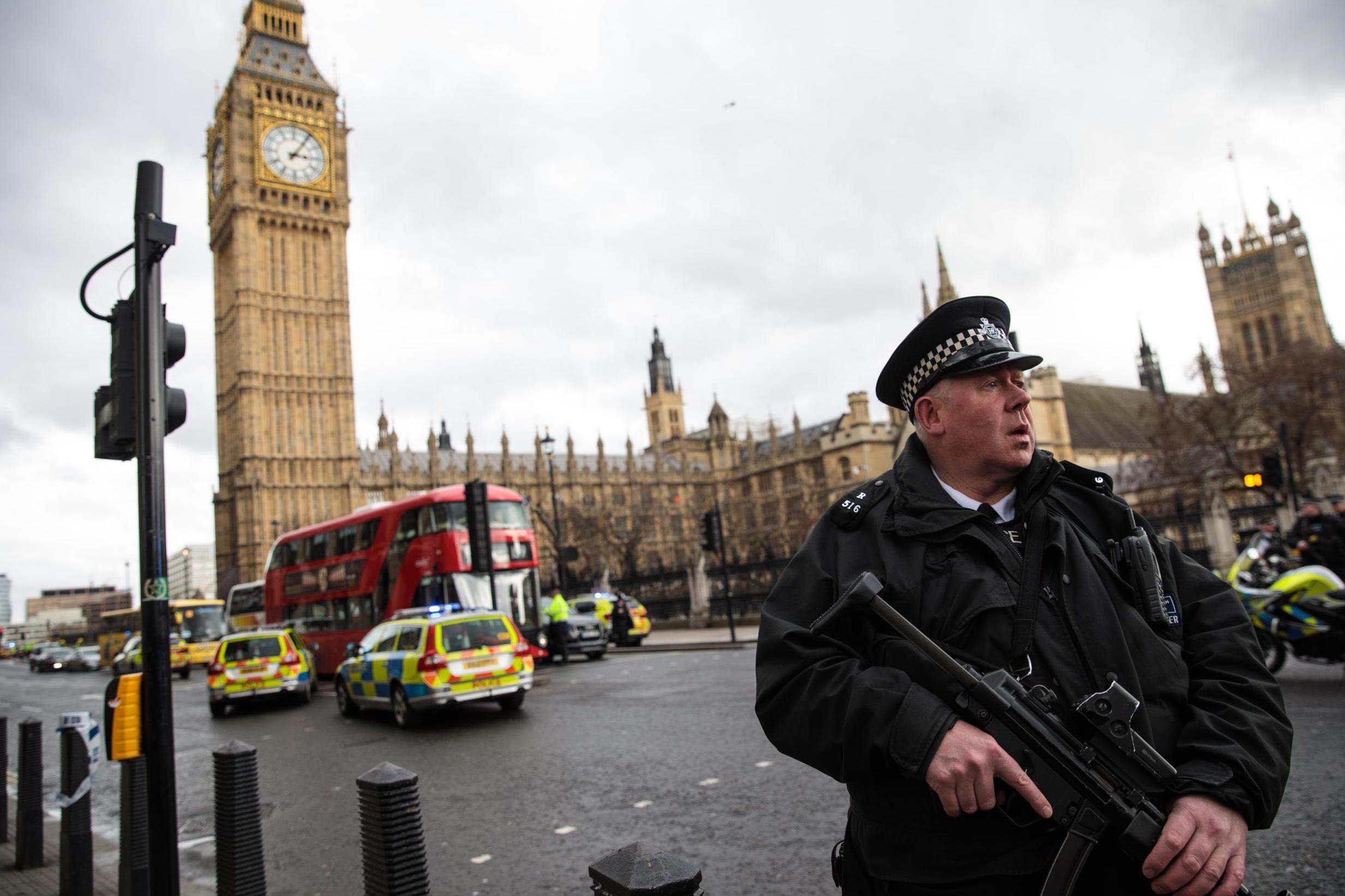 An armed police officer stands guard opposite the tourist attraction of Big Ben