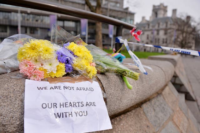 Floral tributes with a message reading 'We are not afraid, our hearts are with you' are seen near a police cordon in Westminster