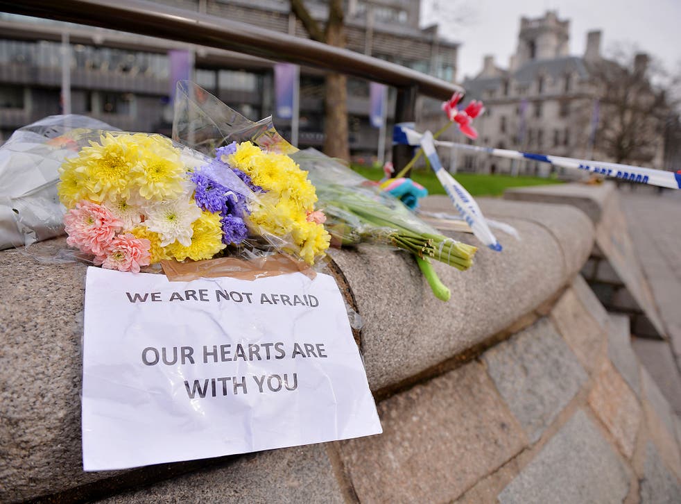 Floral tributes with a message reading 'We are not afraid, our hearts are with you' are seen near a police cordon in Westminster