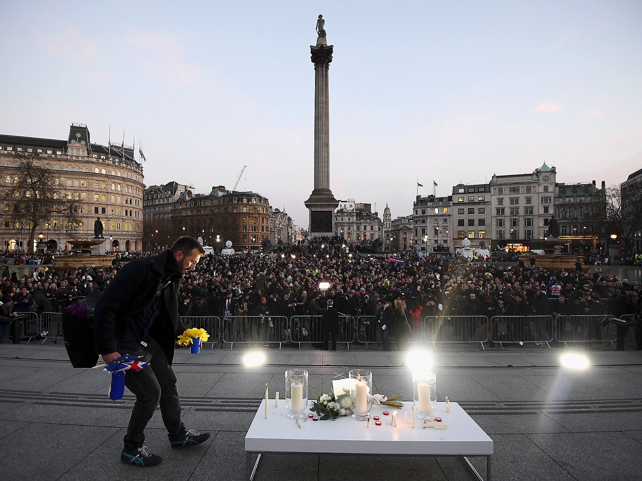A man lays flowers during a candlelit vigil at Trafalgar Square