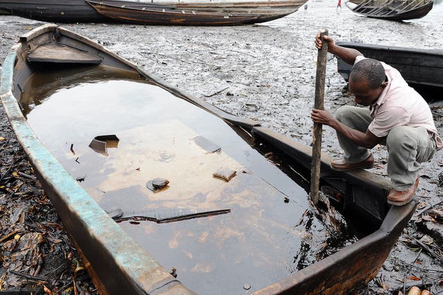 A man from the Bodo community, in Ogoniland, tries to separate with a stick the crude oil from water in a boat after waterways were polluted by oil spills attributed to Shell equipment failure.