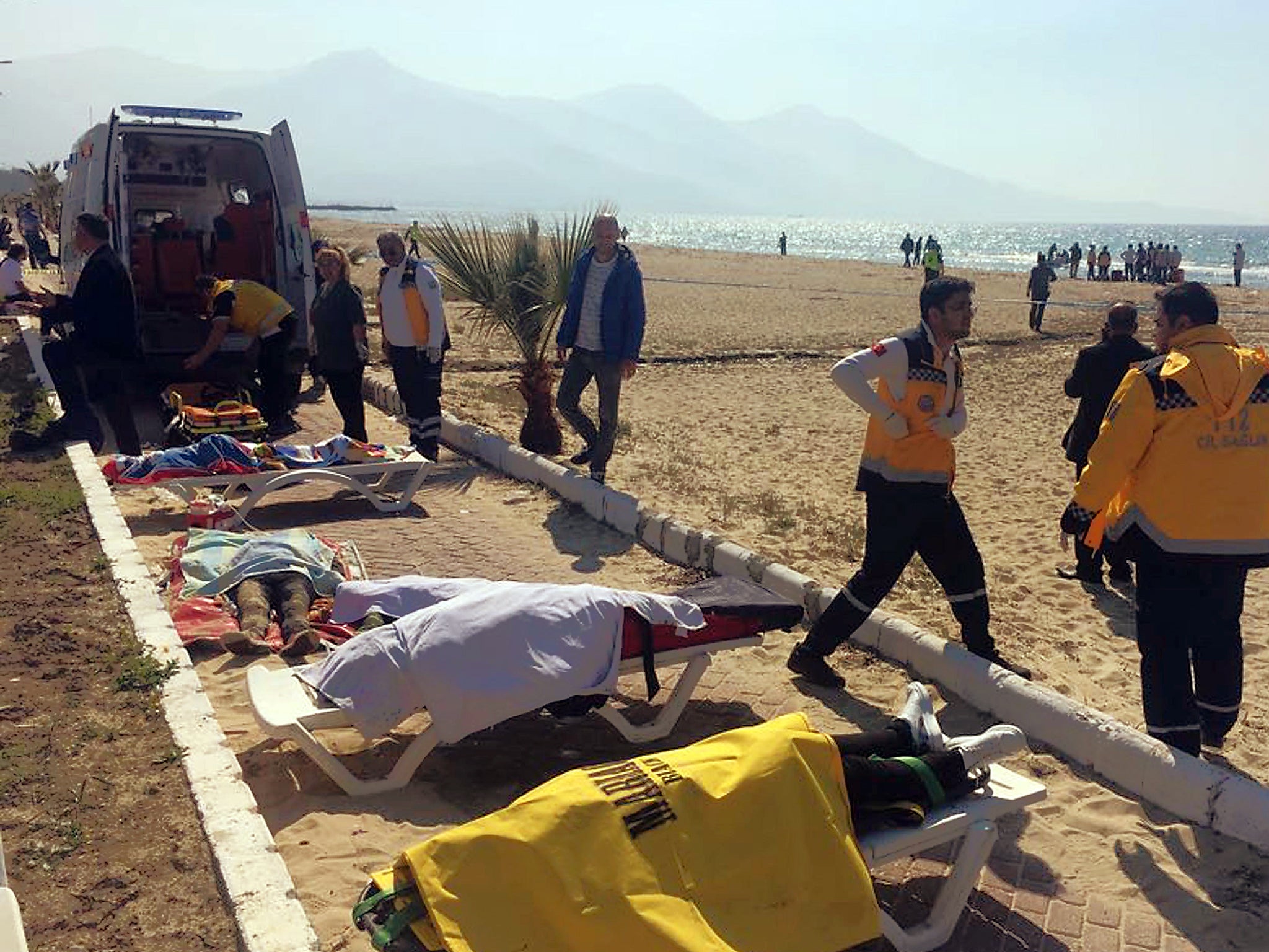 Turkish rescue workers and medics work next to the bodies of migrants laid out near an ambulance in Kusadasi, Turkey