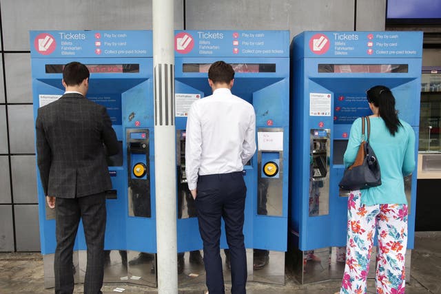Commuters buy train tickets from machines at Finsbury Park station in north London