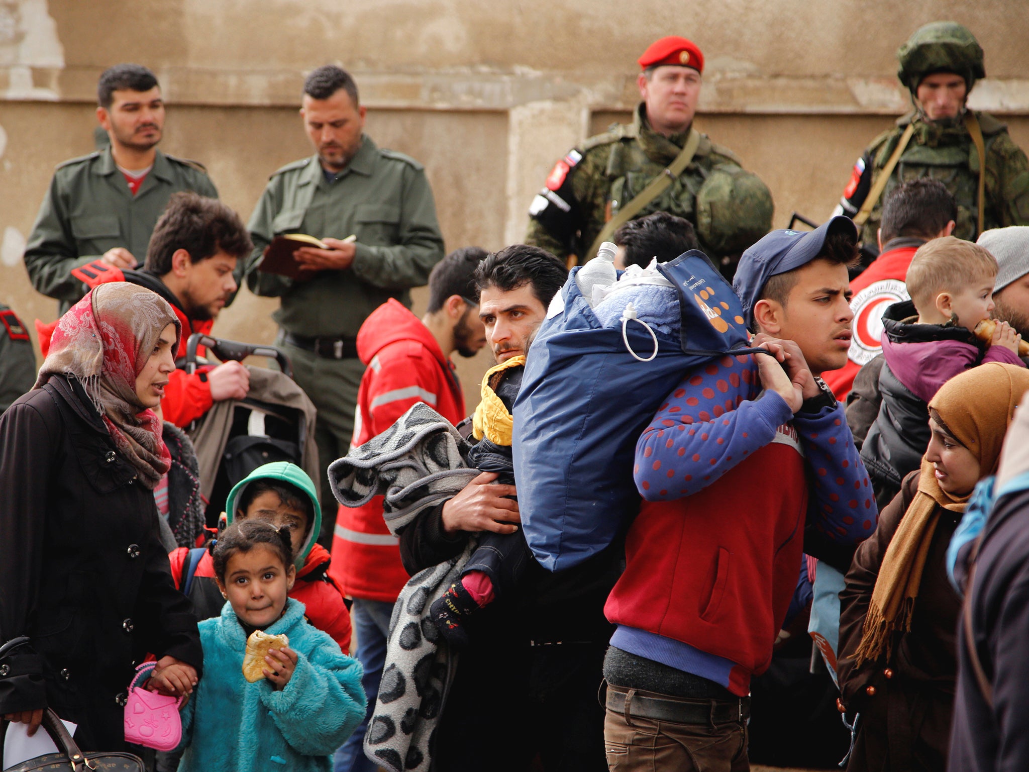 Syrian army and Russian soldiers monitor as rebel fighters and their families evacuate a district of Homs last week