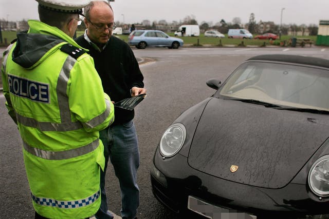 A Police officer hands a leaflet to a driver caught using his telephone whilst driving