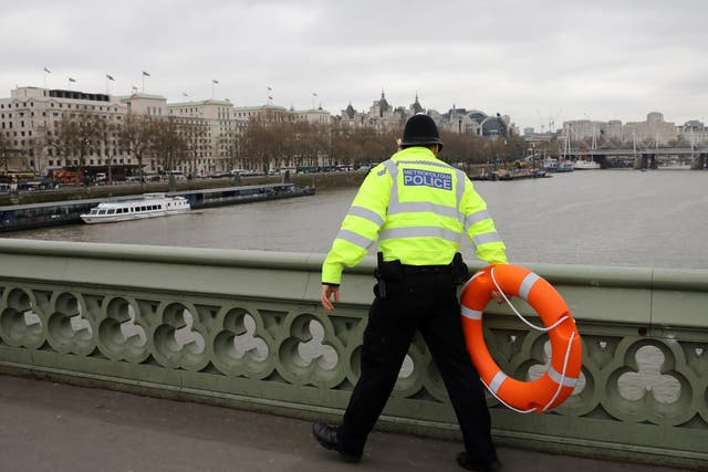 Police officer looks for a person thought to have fallen from Westminster Bridge