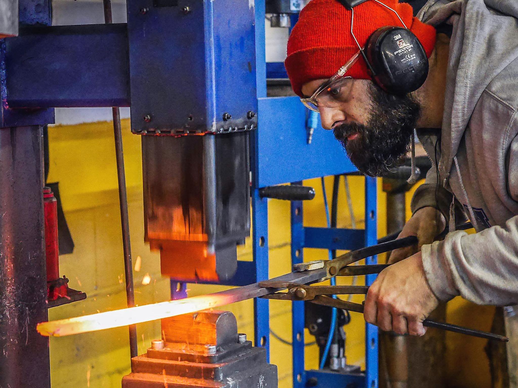 Joel forging the steel with a power hammer