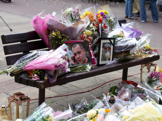 Floral tributes and a photograph of Arek Jozwik on a bench at the shopping centre in Harlow where he was killed
