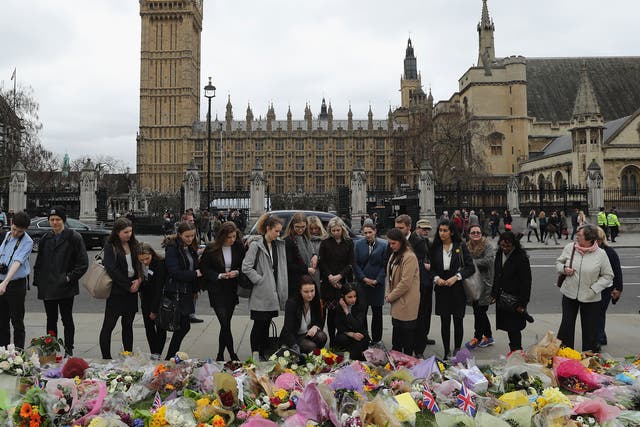 People gather by floral tributes left for the victims of the March 2017 Westminster terrorist attack