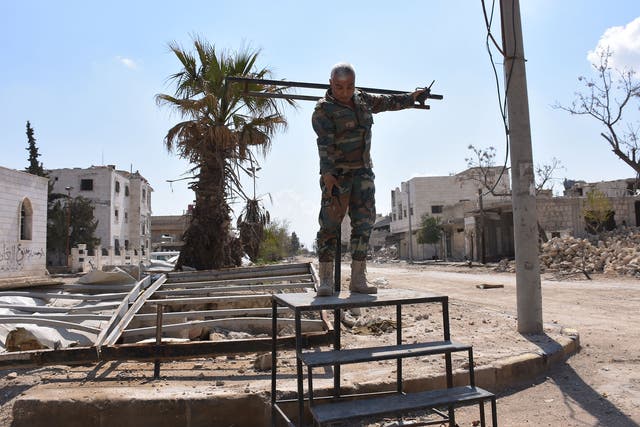 A Syrian soldier demonstrates how the crucifixion stand erected and used by Isis works