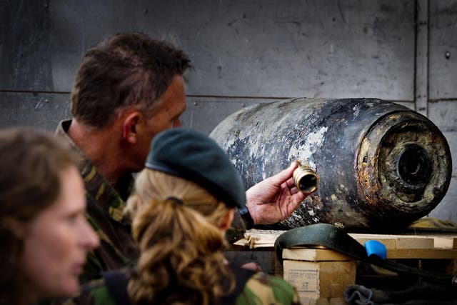 Members of the Dutch Explosive Ordnance Disposal unit stand next to a 500-pound bomb from World War II in Wannenaar, the Netherlands