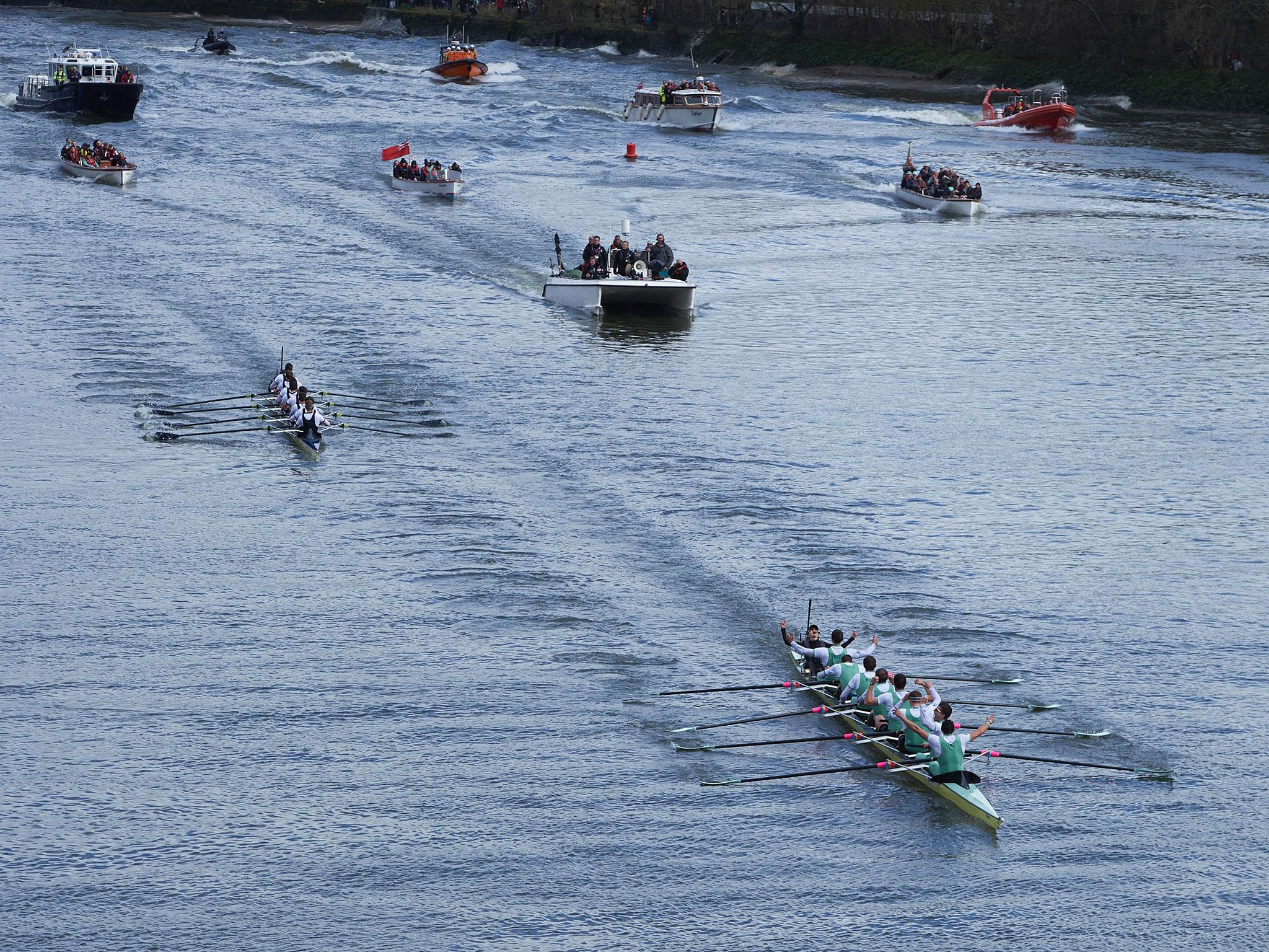 The Cambridge (near R) crew lead Oxford crew as they row in to toward the finish line with the flotilla following in the annual men's boat race between Oxford and Cambridge University on the River Thames in London on March 27, 201