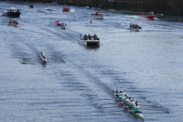The Cambridge (near R) crew lead Oxford crew as they row in to toward the finish line with the flotilla following in the annual men's boat race between Oxford and Cambridge University on the River Thames in London on March 27, 201