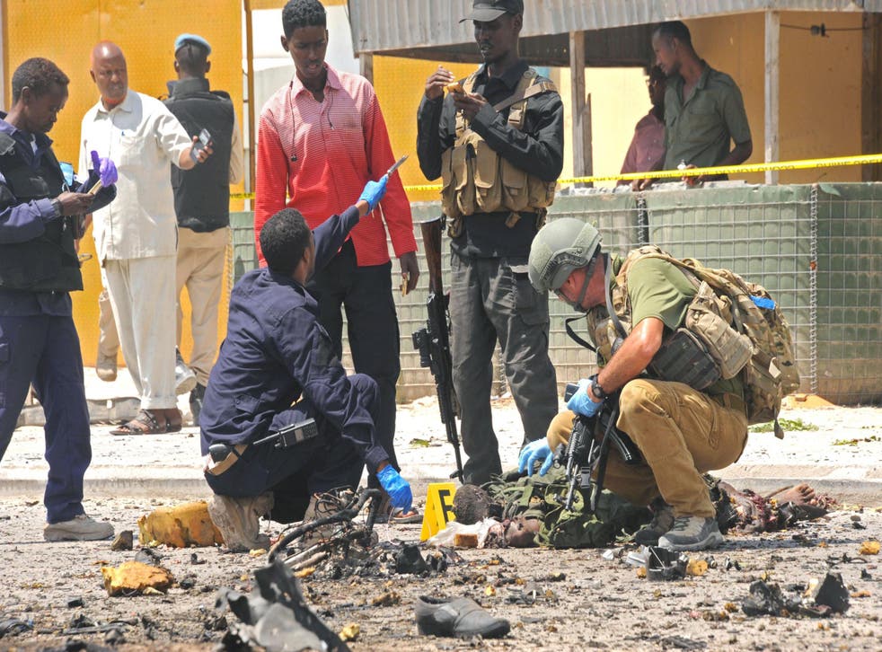 A foreign security officer checks a body at the scene of a suicide attack in Mogadishu, on 31 July, 2016. MOHAMED ABDIWAHAB/AFP/Getty Images
