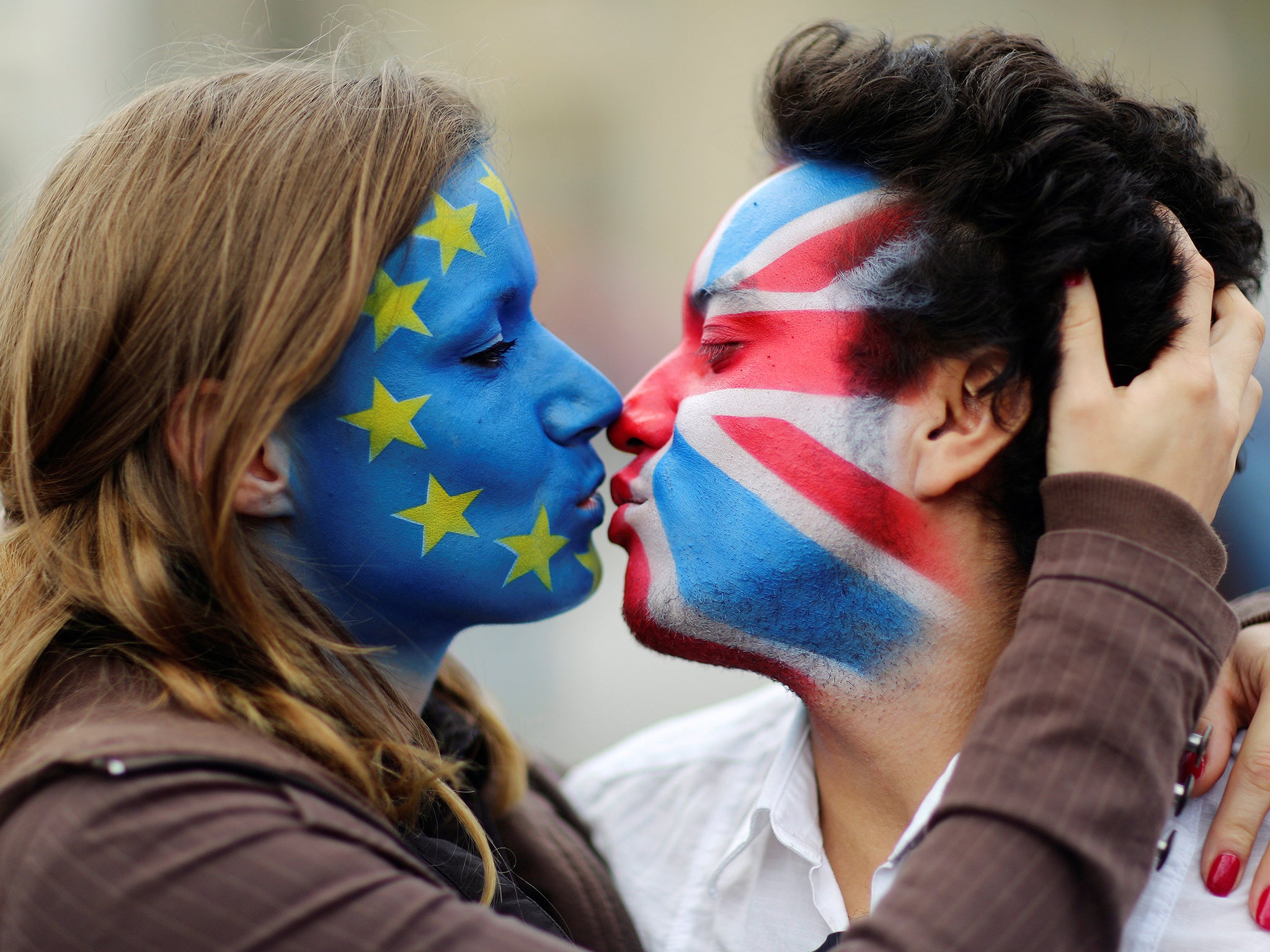 Two activists with the EU flag and Union Jack painted on their faces kiss each other in front of Brandenburg Gate to protest against the British exit from the European Union, in Berlin