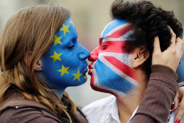 Two activists with the EU flag and Union Jack painted on their faces kiss each other in front of Brandenburg Gate to protest against the British exit from the European Union, in Berlin