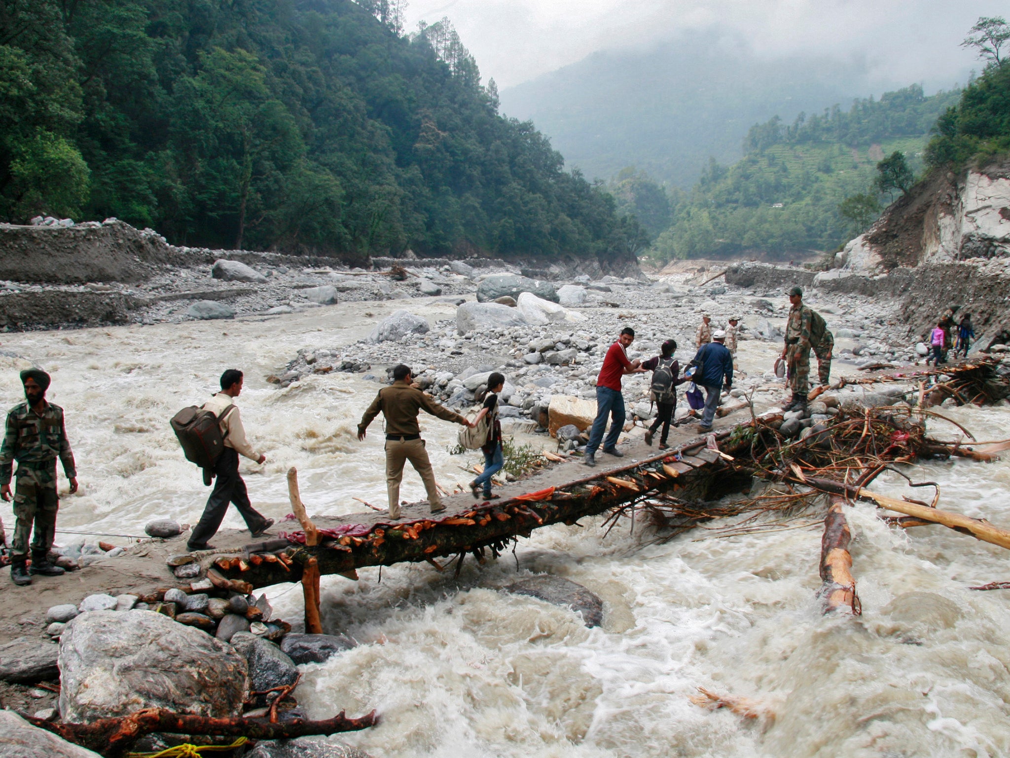 Indian army personnel help stranded people cross a flooded river after heavy rains in the Himalayan state of Uttarakhand, Flash floods and landslides killed thousands.