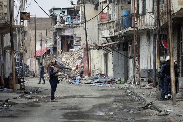 An Iraqi federal police officer stands guard on a Mosul street