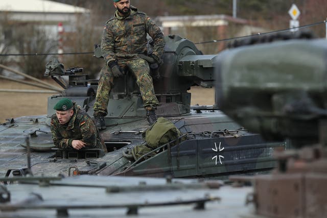 Soldiers of the Bundeswehr, the German armed forces, prepare to drive Marder light tanks onto a train for transport to Lithuania