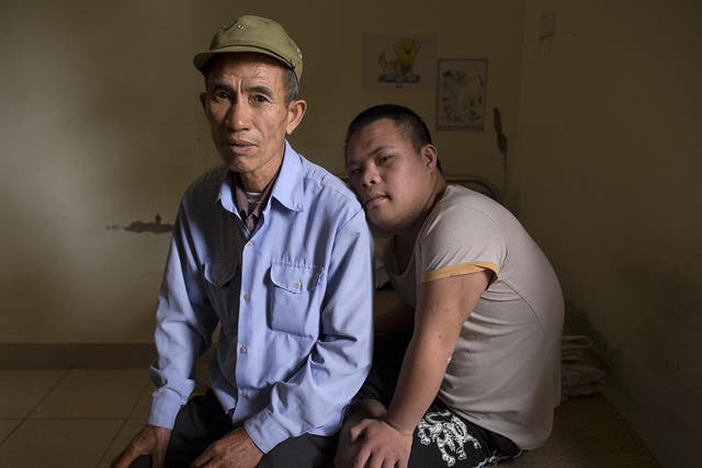 63-year-old former soldier, Nguyen Hong Phuc, sits on the bed with his son Nguyen Dinh Loc, 20, who is recovering from tumour surgery at a hospice for Agent Orange victims (Damir Sagolj/Reuters)
