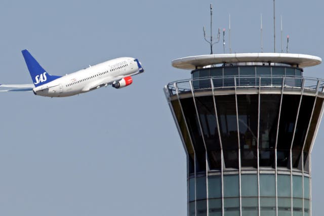 A passenger plane flies by an air traffic control tower after taking off from Charles de Gaulle International Airport