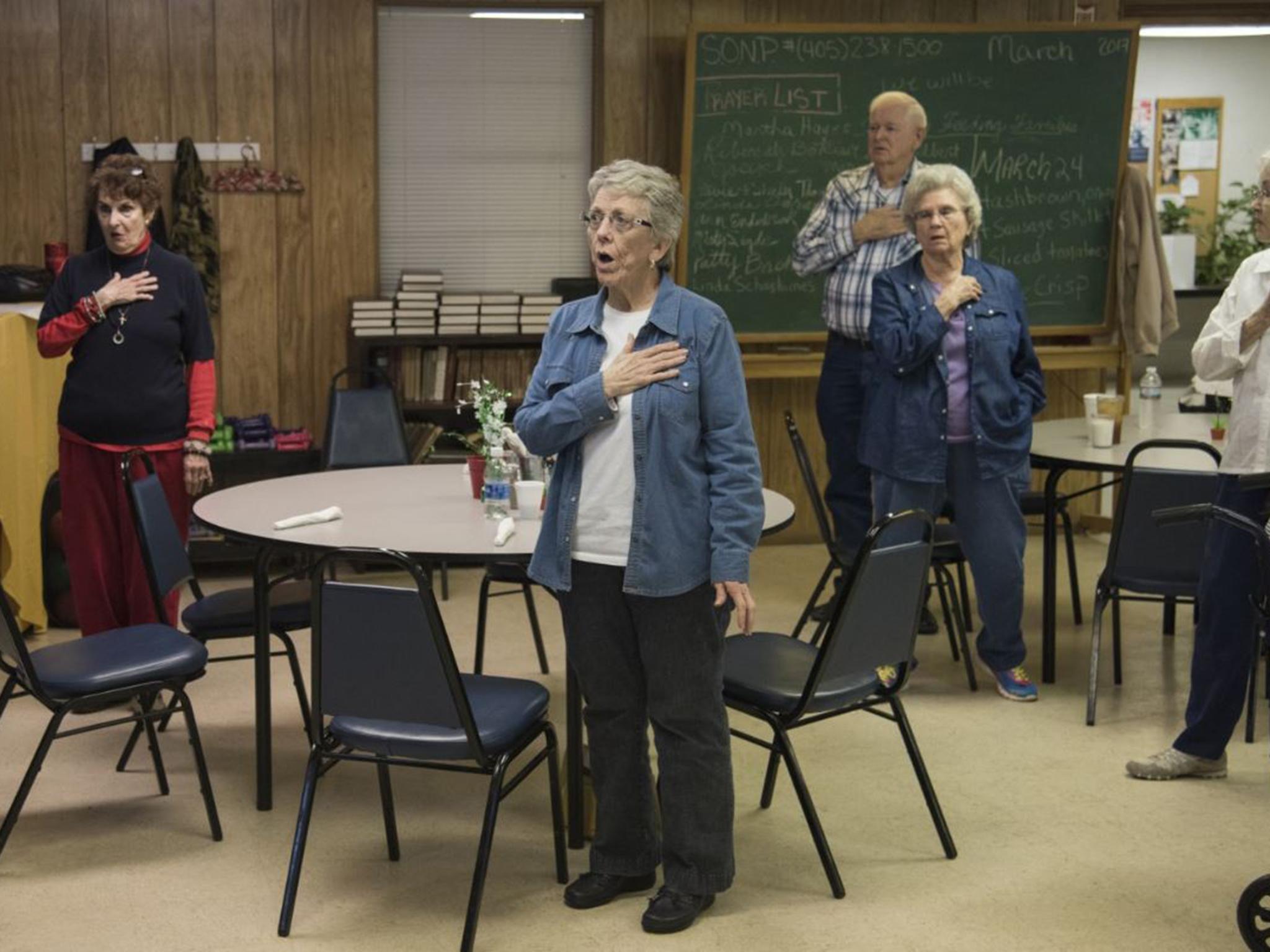 Residents stand for the Pledge of Allegiance before lunch at the Robert T Davis Senior Centre in Durant