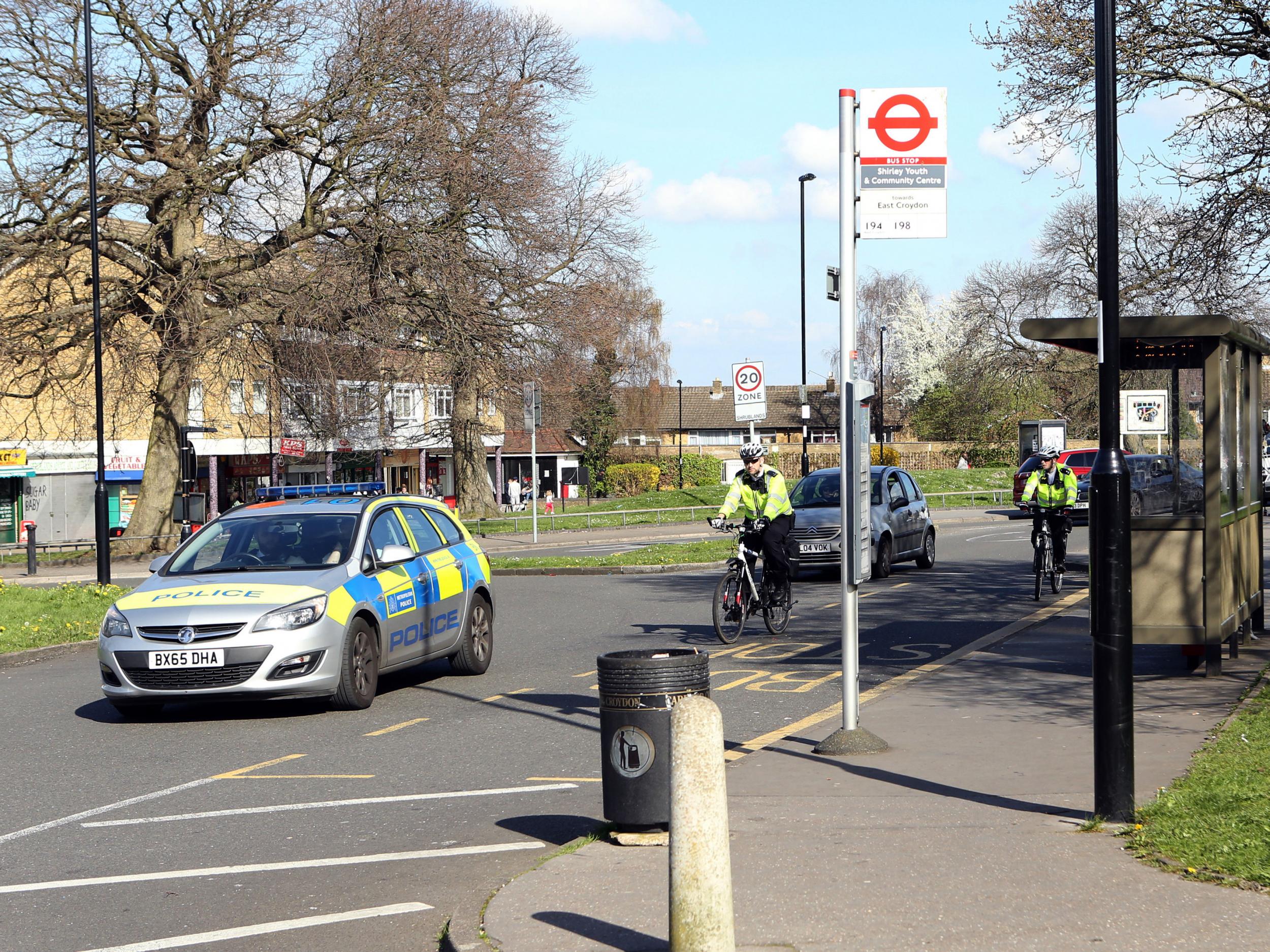Police officers pass the bus stop in Croydon, south London, where a teenage asylum seeker was victim of a suspected hate attack
