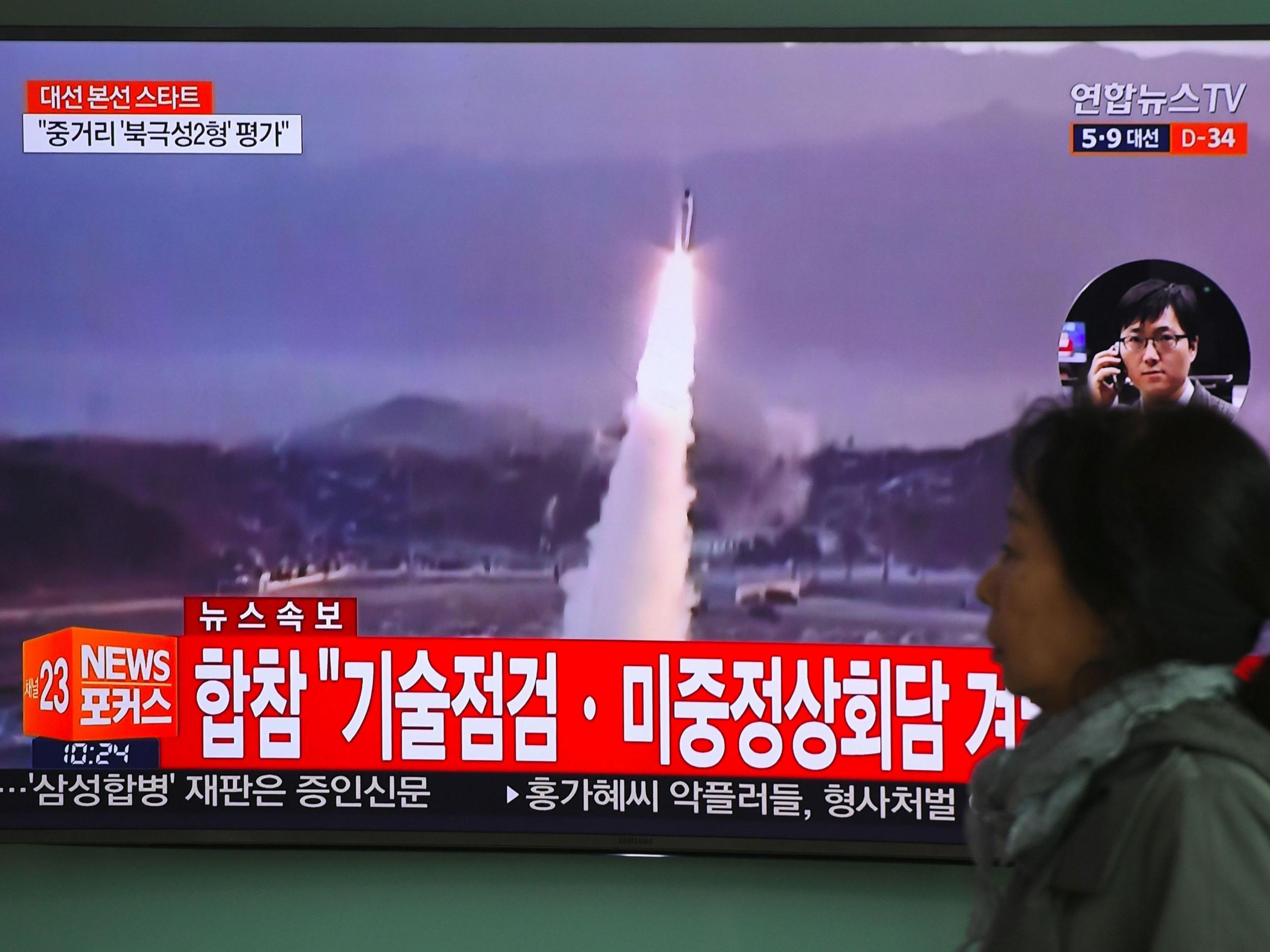 A woman in Seoul walks past a television screen showing file footage of a North Korean missile launch on the day of the failed test
