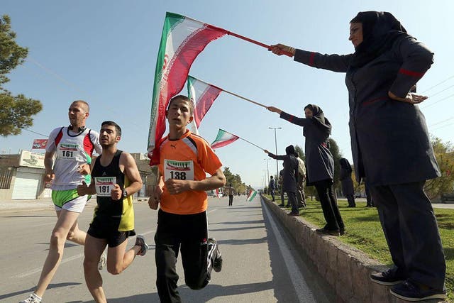 Iranian women wave their national flag as they support Iranian and foreign runners competing in Iran's first internation marathon in Marvdasht on April 9, 2016